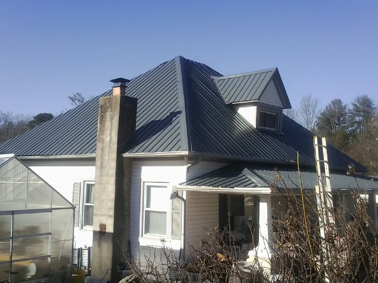 Dark blue standing seam metal roof on a white farmhouse with dormer — Slate & Tile Roof Repair by Roofing Brothers in Silverlake