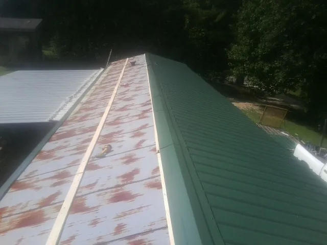 Old rusted panels beside newly installed green metal roofing — Wind Damage Roof Repair by Roofing Brothers in Silverlake