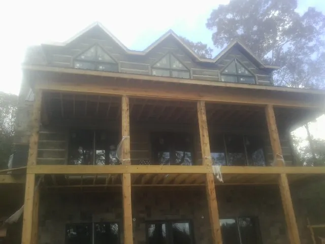 Dormers and porch framing on a large log home under construction — Roof Coating work by our crew in Silverlake