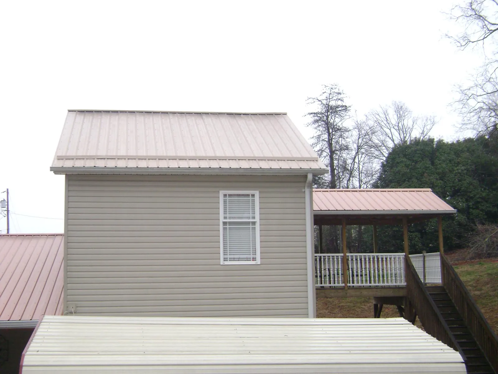 Tan metal roofs on a two story addition and attached porch, from a Roof Replacement job in Silverlake